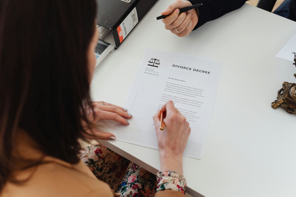 woman signing divorce settlement document