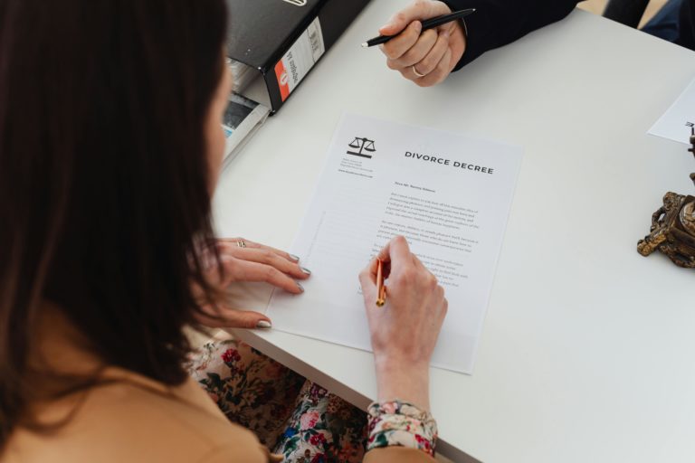 woman signing divorce settlement document